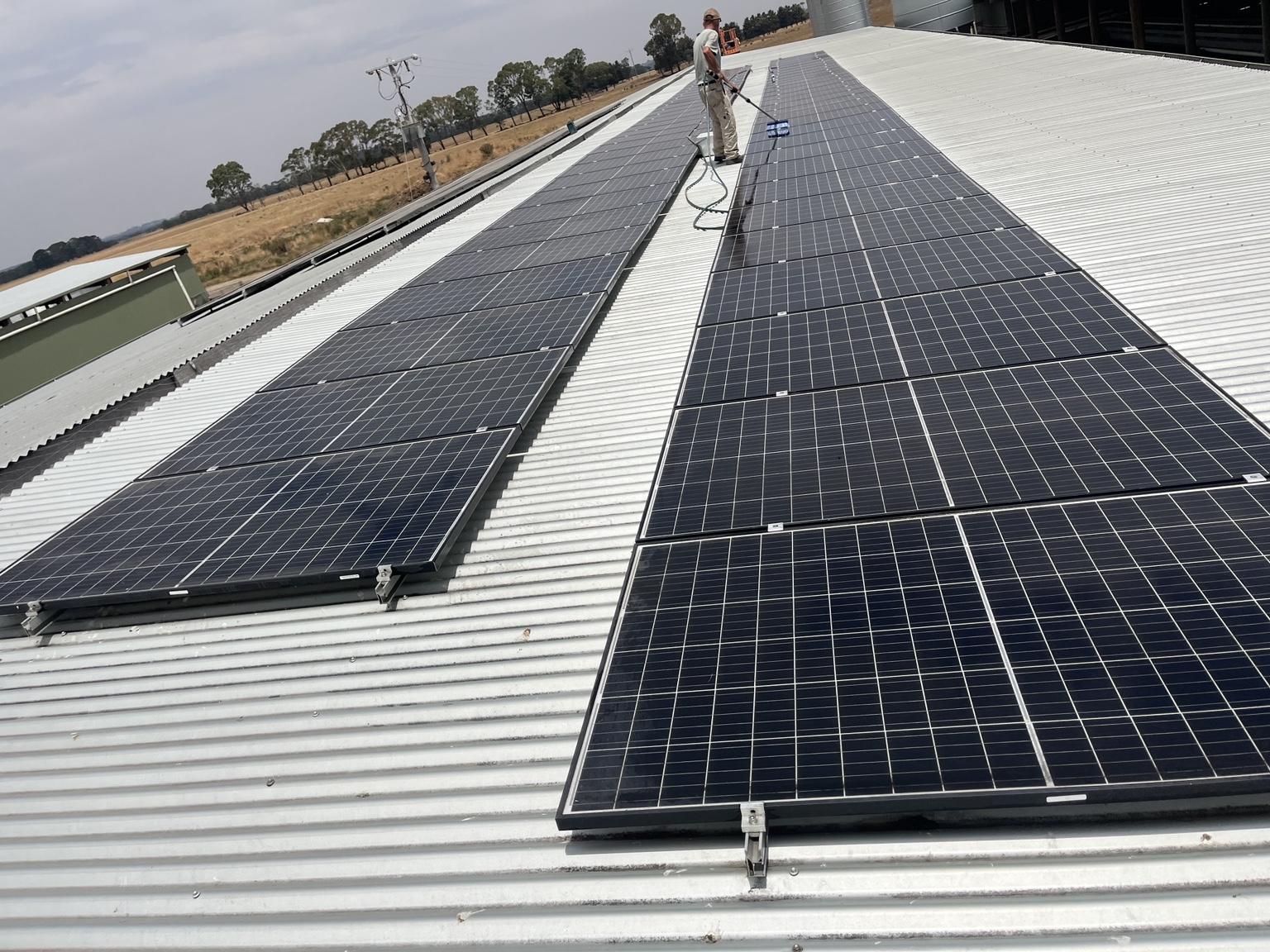 Worker cleaning commercial solar panel array